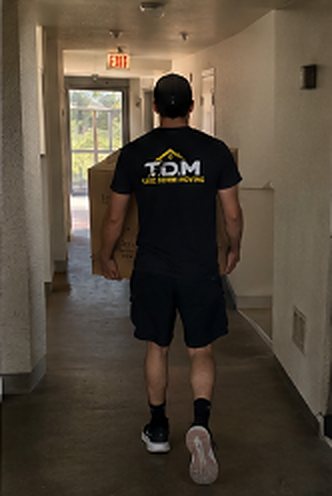 T.D.M mover carrying a box down a hallway